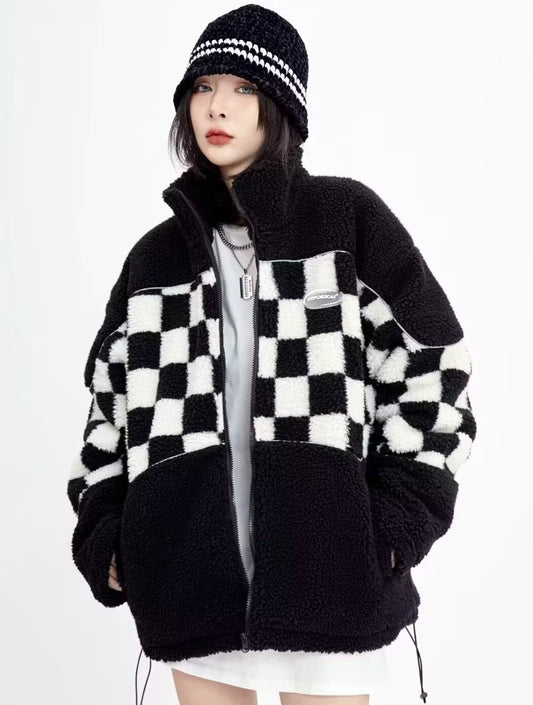 チェッカーフラッグ柄のボアジャケットを着用した斜め前からのポーズ。スタンドカラーのデザインとオーバーサイズなシルエット。