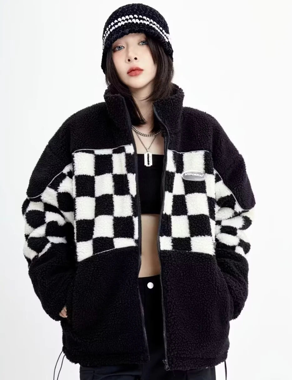 ジップアップのブロックチェックジャケットを着用した正面写真。ネックレスや帽子などの小物使いが映えるデザイン。