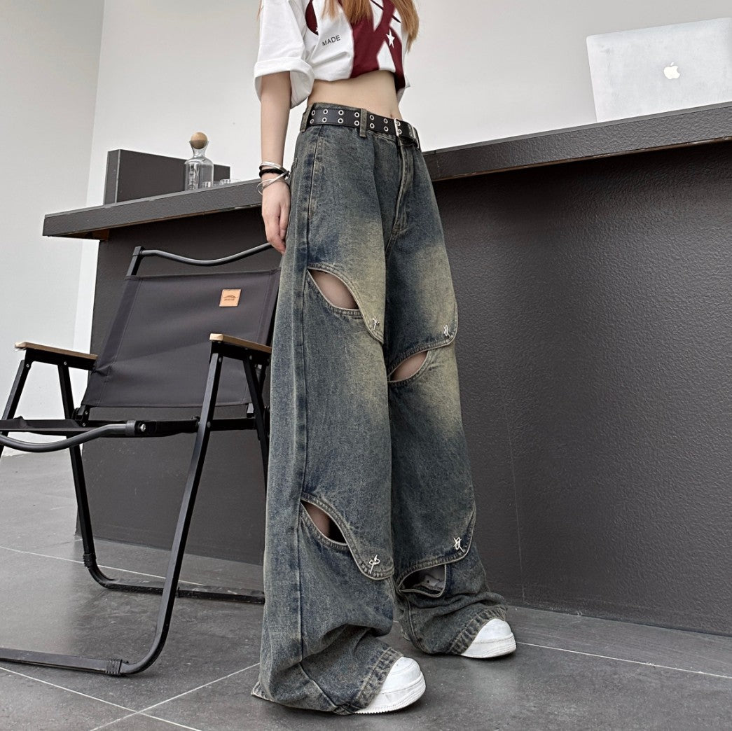 斜め前から撮影したブラックのカットアウトワイドデニムパンツ。複数のスリットと金具ディテールが際立つストリートコーデ。