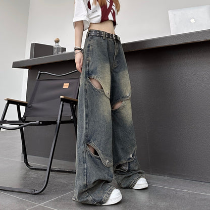 斜め前から撮影したブラックのカットアウトワイドデニムパンツ。複数のスリットと金具ディテールが際立つストリートコーデ。