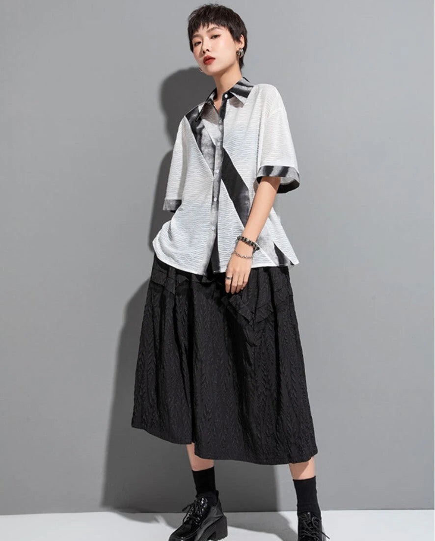 ホワイトの斜めタイダイ柄シアー半袖シャツと黒スカートを合わせた全身コーデ