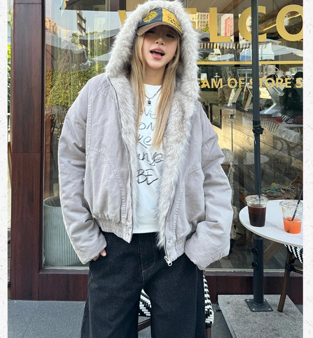 外のカフェ前で、ブルゾンを着用し口を開けて話すようなポーズの女性。正面からの全身ショット。