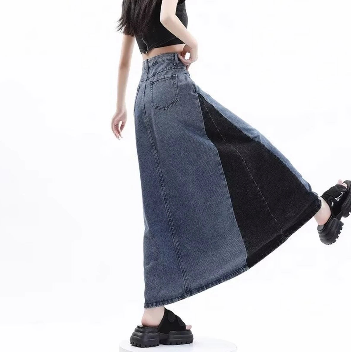 グレーのロングデニムスカートを着たモデルの後ろ姿。片足を上げ、動きのあるポーズ。