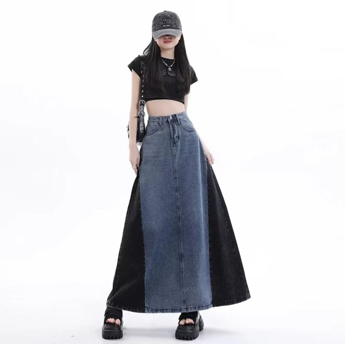 グレーのロングデニムスカートを着たモデル。キャップを被り、黒いショルダーバッグを肩にかけた立ち姿。