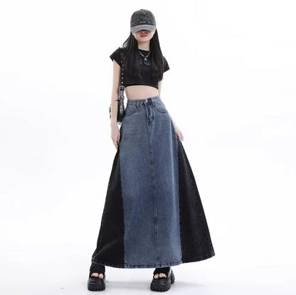 グレーのロングデニムスカートを着たモデル。キャップを被り、黒いショルダーバッグを肩にかけた立ち姿。