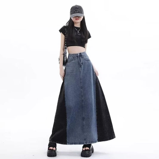 グレーのロングデニムスカートを着たモデル。キャップを被り、黒いショルダーバッグを肩にかけた立ち姿。