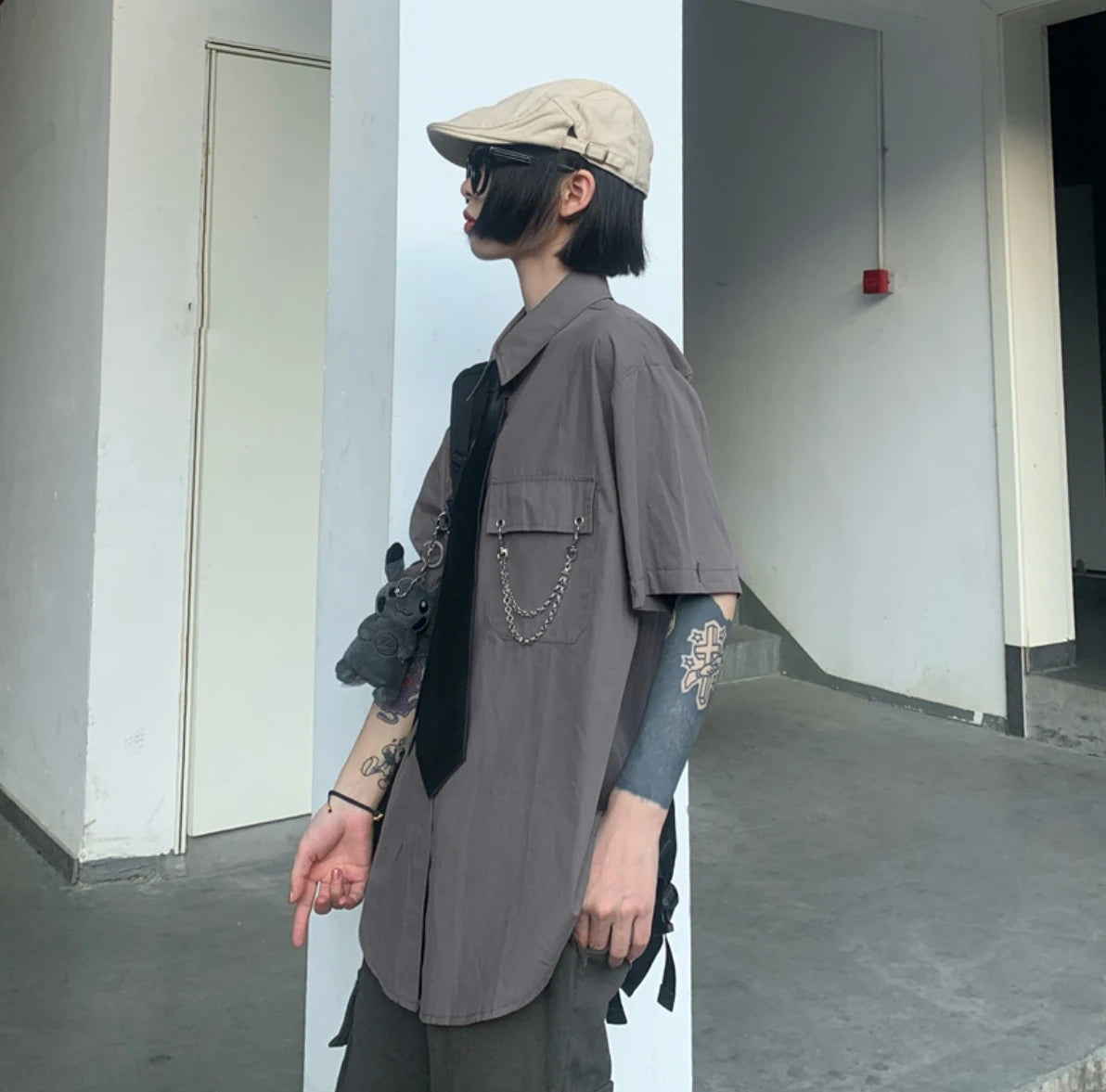 グレーのネクタイ付きシャツを着たモデル。キャスケットとサングラス着用。横顔のアップ。