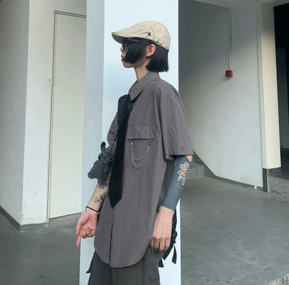 グレーのネクタイ付きシャツを着たモデル。キャスケットとサングラス着用。横顔のアップ。