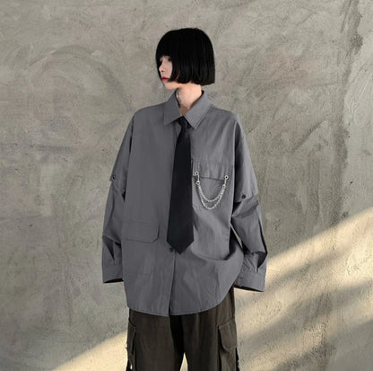 グレーのネクタイ付きシャツを着たモデル。長袖状態で着用。横を向いた立ち姿。