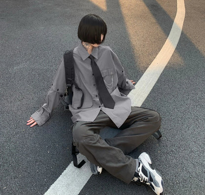 グレーのネクタイ付きシャツを着たモデル。道路（アスファルト）に座り込んでいる全身ショット。