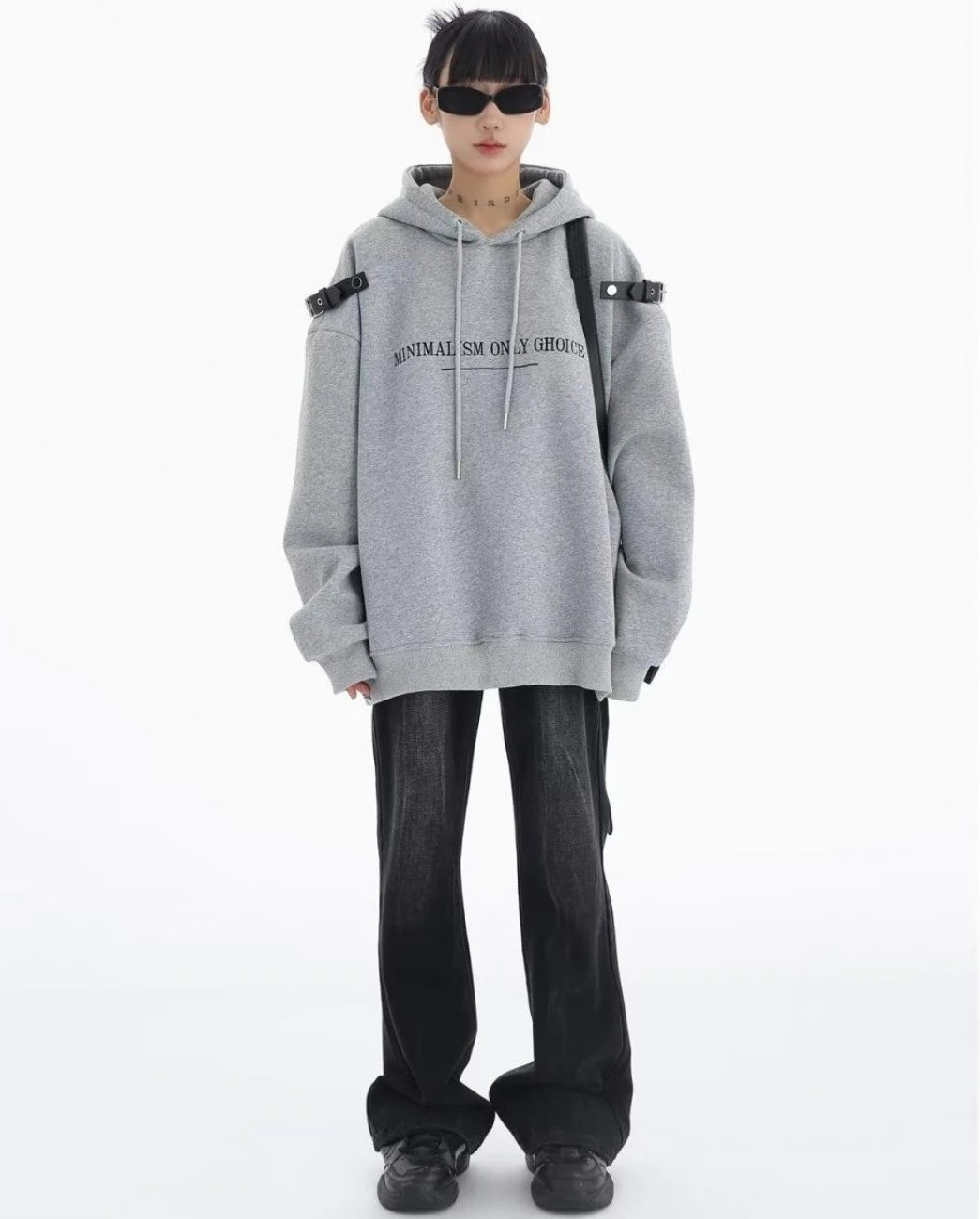 グレーのショルダーベルト付きオーバーサイズパーカーとブラックデニムの正面全身コーデ。シンプルに着こなしたカジュアルストリートスタイル。