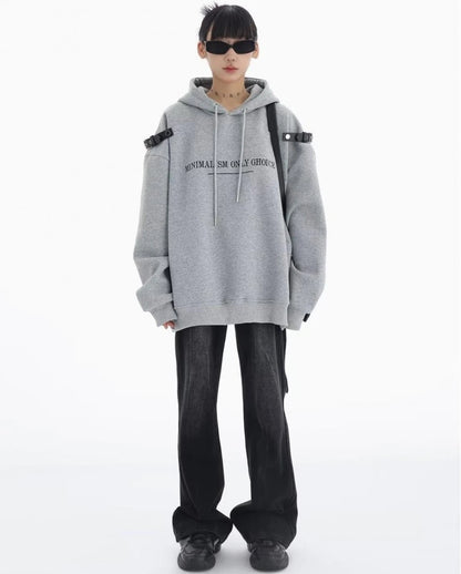 グレーのショルダーベルト付きオーバーサイズパーカーとブラックデニムの正面全身コーデ。シンプルに着こなしたカジュアルストリートスタイル。