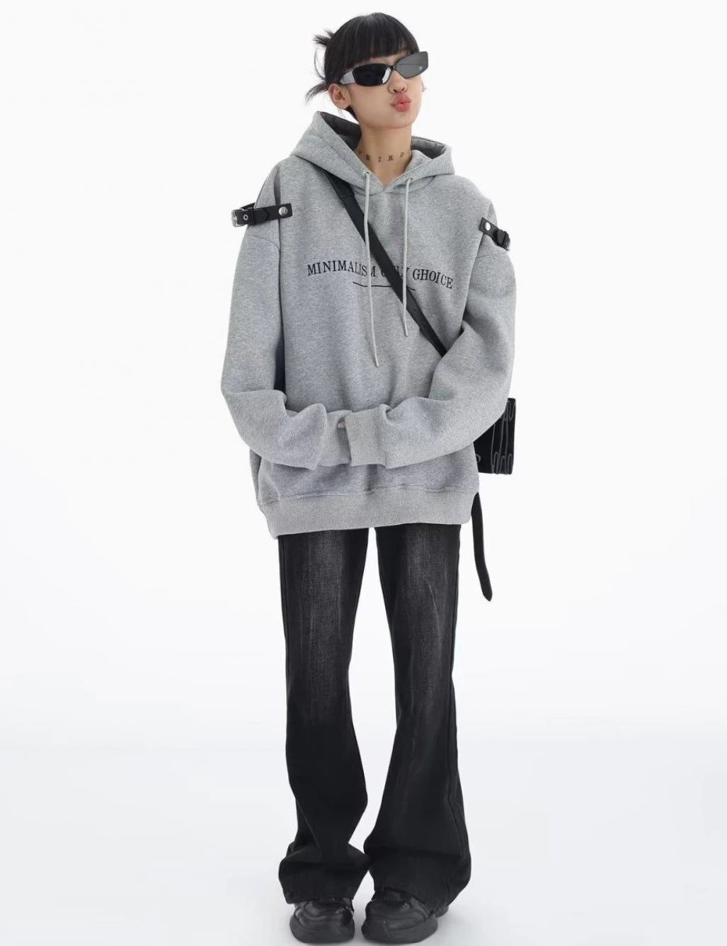 グレーのショルダーベルト付きオーバーサイズパーカーとブラックデニムの全身コーデ。ゆったりシルエットのストリートスタイル。