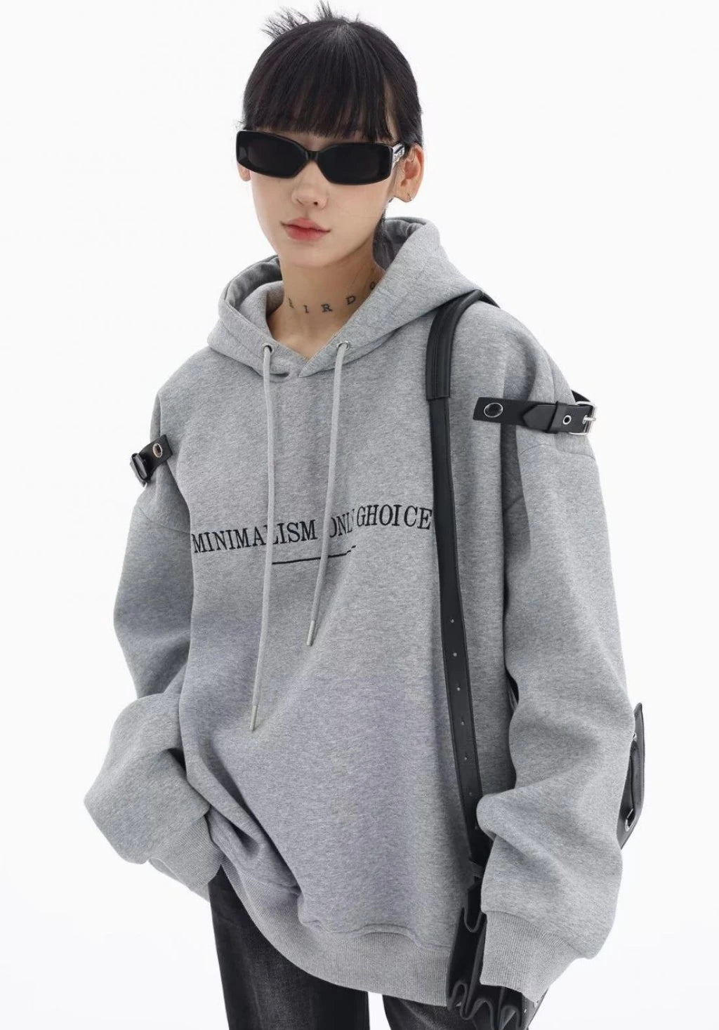グレーのショルダーベルト付きオーバーサイズパーカーにブラックデニムを合わせた上半身コーデ。サングラスでモードなストリートスタイル。