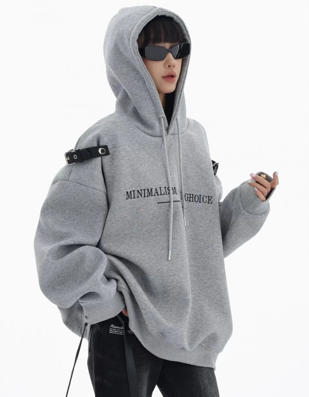 グレーのショルダーベルト付きオーバーサイズパーカーのフードをかぶった横向きコーデ。袖にボリュームのあるラフなストリートスタイル。