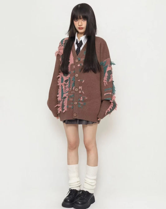 ダメージニットカーディガンとルーズソックス（レッグウォーマー）を合わせた全身コーディネート。口元に手を当てたポーズ。