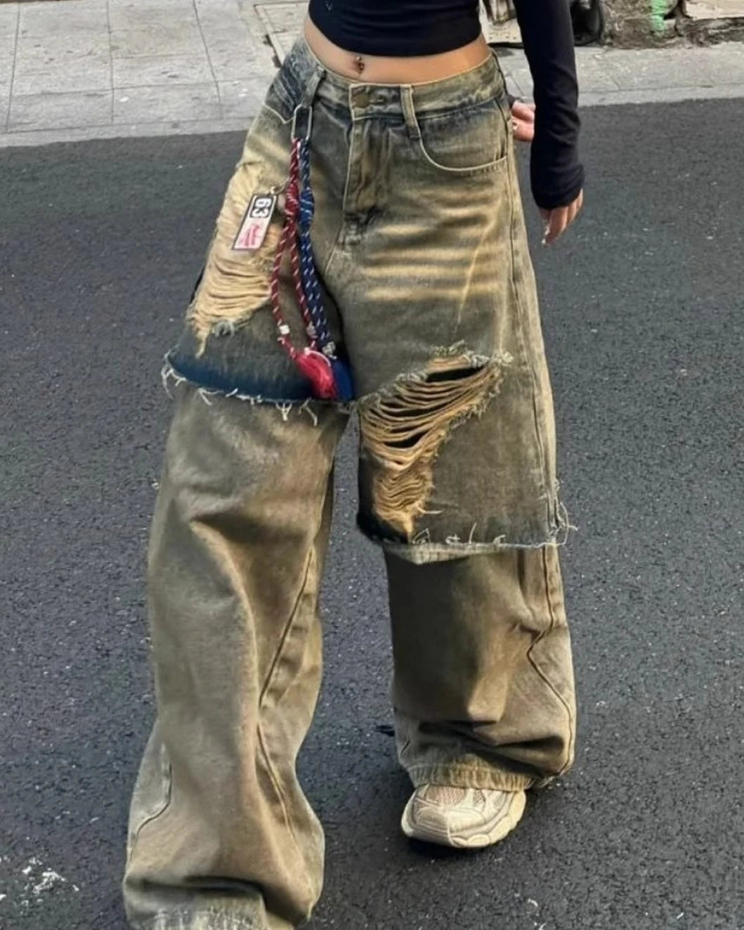 ウォッシュ加工が施されたグランジ風ワイドデニムの全身写真。太もも部分の大きな破れと切りっぱなしのデザイン。