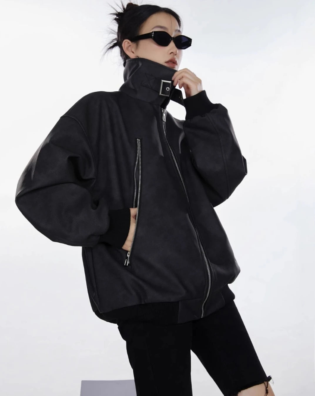 ブラックのスタンドカラージャケットを着た女性が横向きで襟元に手を添える着用写真