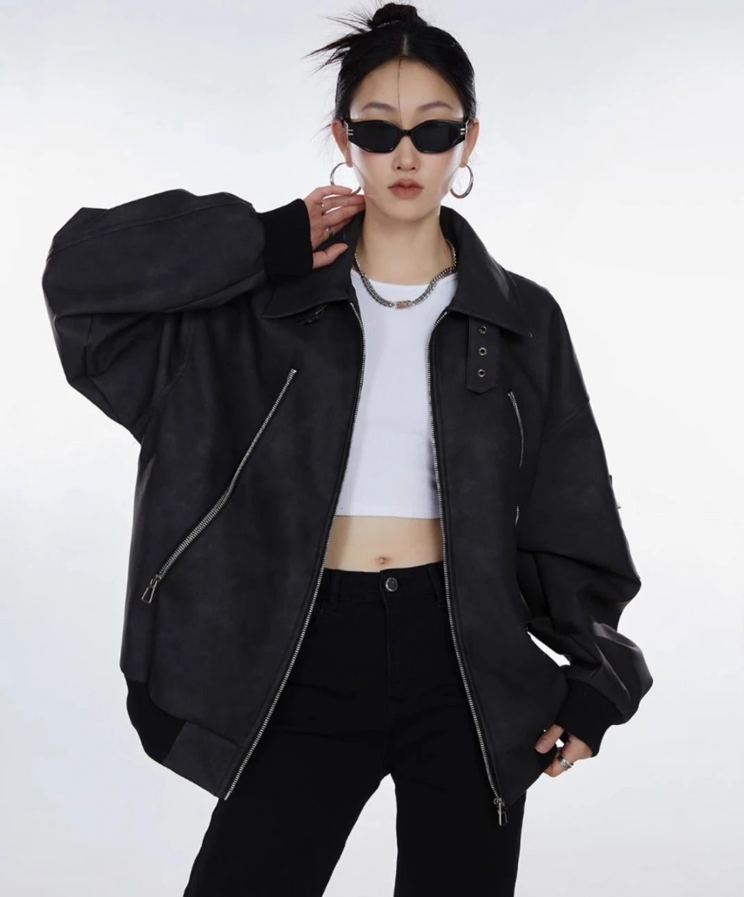 ブラックジャケットを前開きで羽織り白トップスを見せた女性のウエストアップ写真