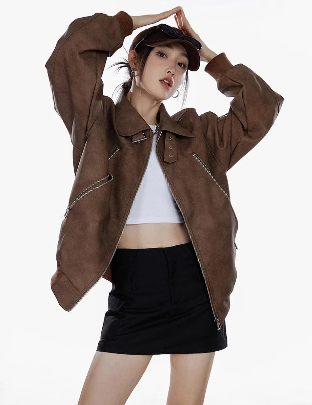 ブラウンのオーバーサイズジャケットを着た女性が腕を上げたポーズのウエストアップ写真