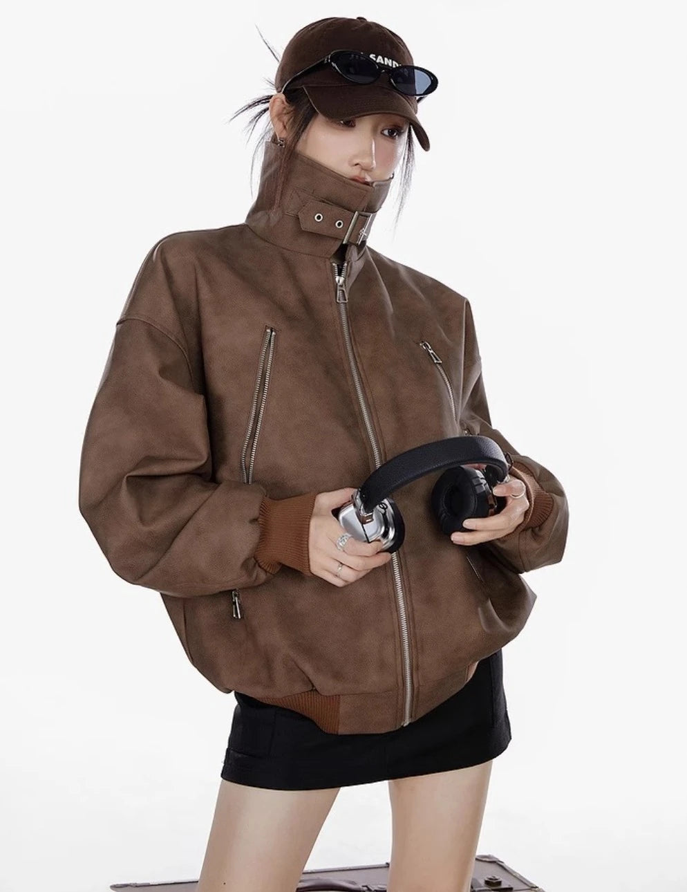 ブラウンのスタンドカラージャケットを着た女性がヘッドホンを両手で持つ着用写真