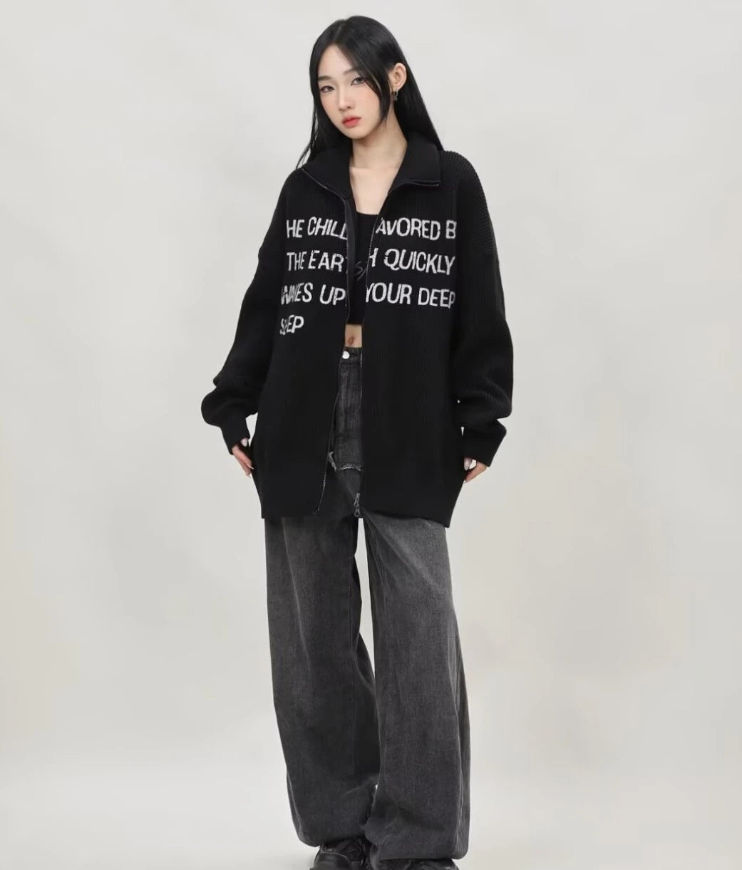 ブラックの英字メッセージジップニットカーディガンのジップを少し開け、インナーを見せたレディースモデルの正面全身スタイリング