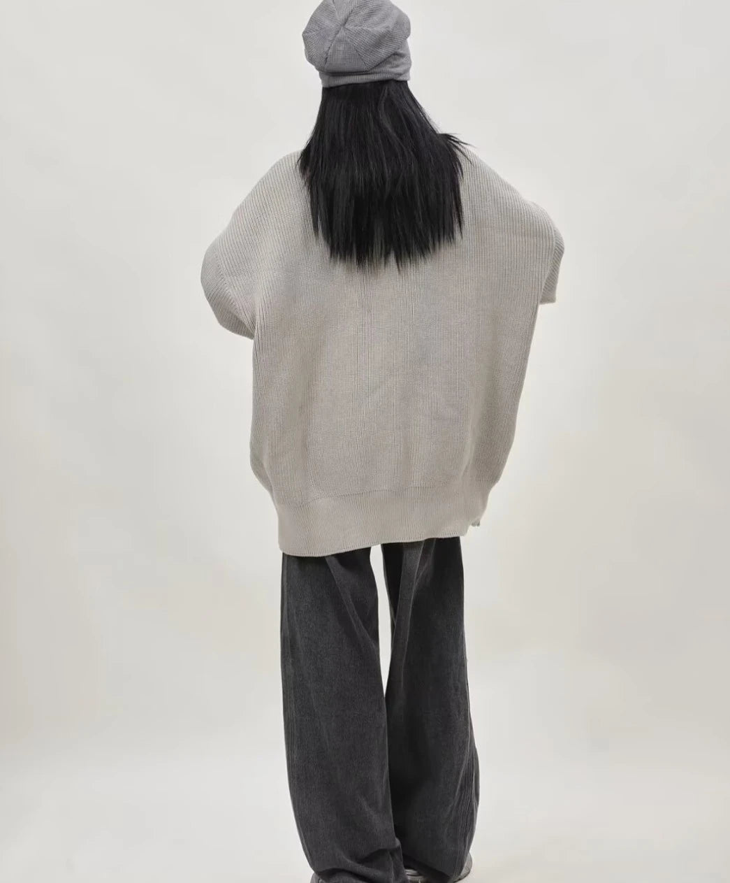 グレーのオーバーサイズジップニットカーディガンを着たレディースモデルの後ろ姿とゆったりとしたバックシルエット