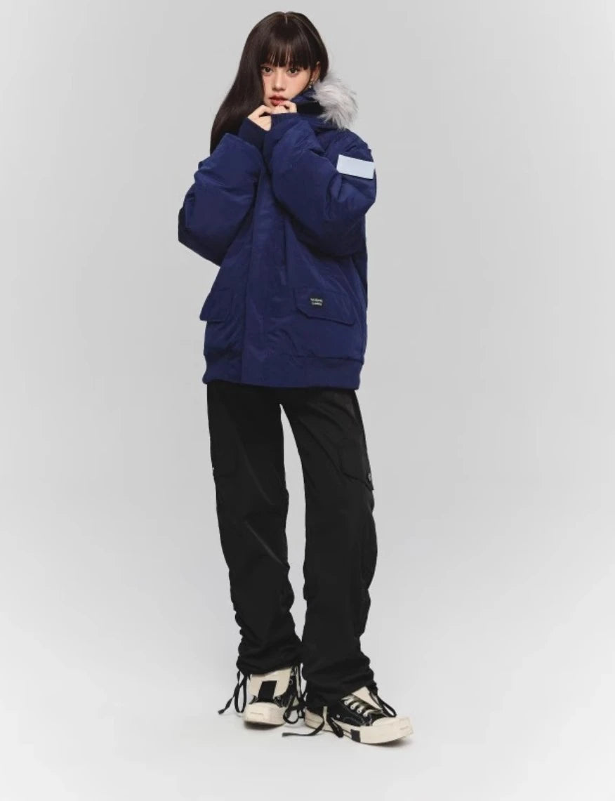 ネイビーのダウンと黒のワイドカーゴパンツの全身コーデ。フードに手を添えるポーズ。