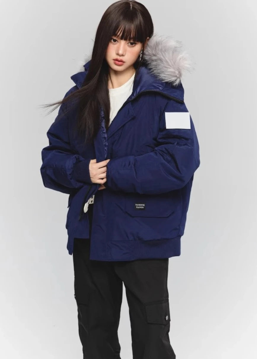 ネイビーのファー付きダウンジャケットを着たモデルの全身。白Tシャツと黒いカーゴパンツのカジュアルコーデ。