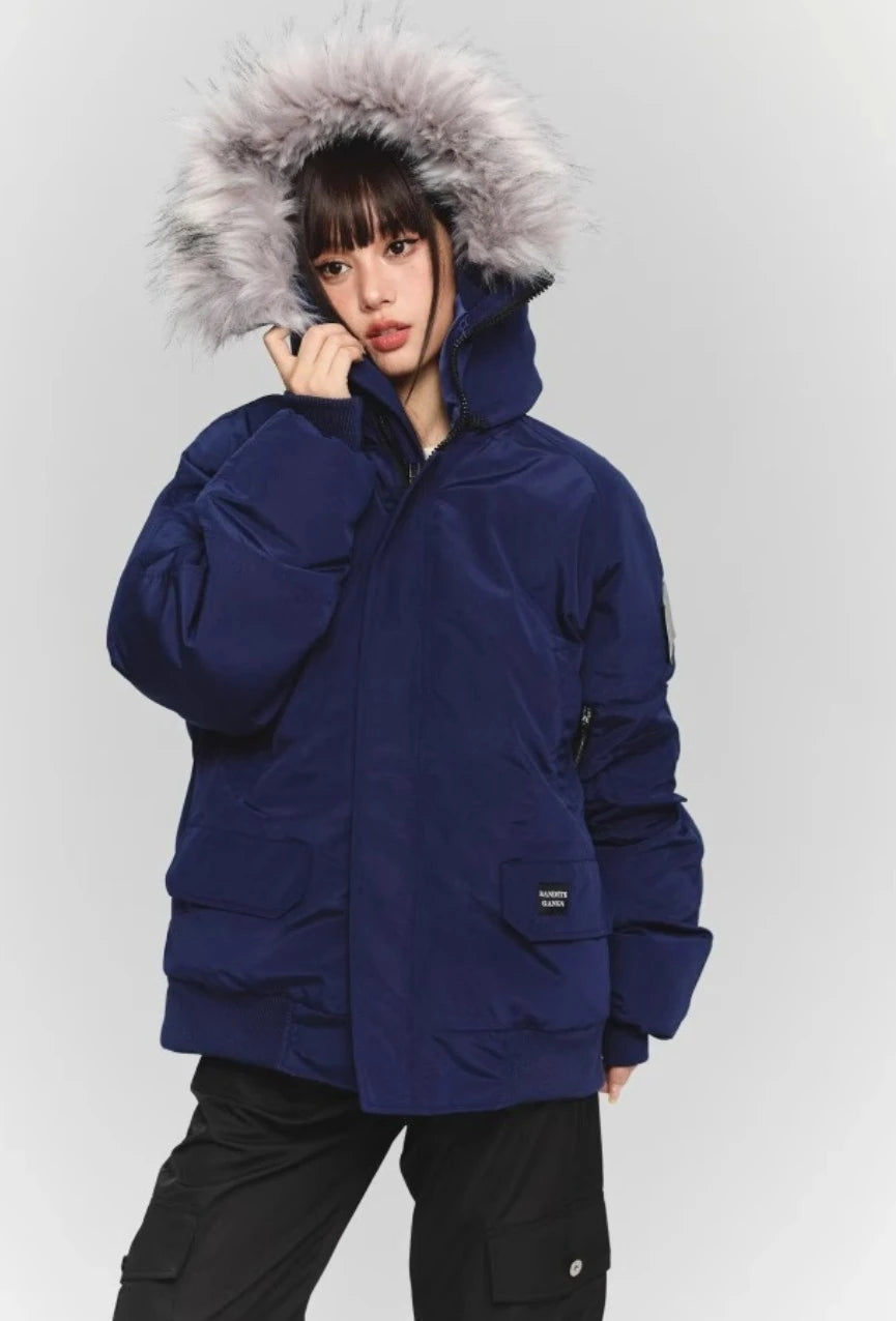 ネイビーのファー付きダウンジャケットを着た女性モデルのクォーターショット。襟元に手を添えるポーズ。