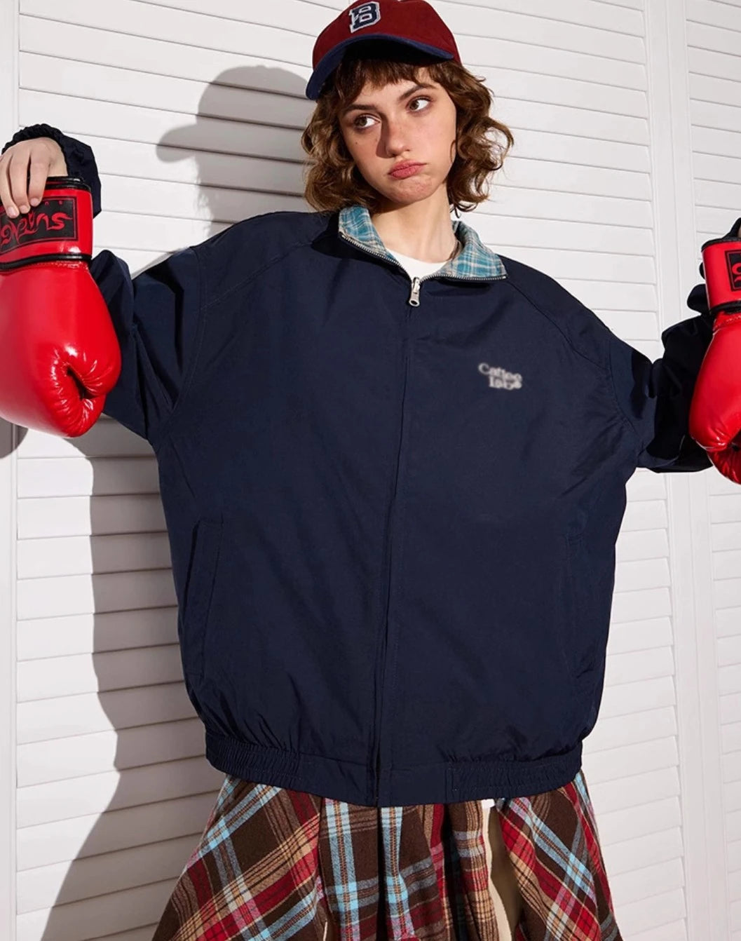 ネイビー無地側のリバーシブルジャケットを着たモデル。ボクシンググローブ着用。
