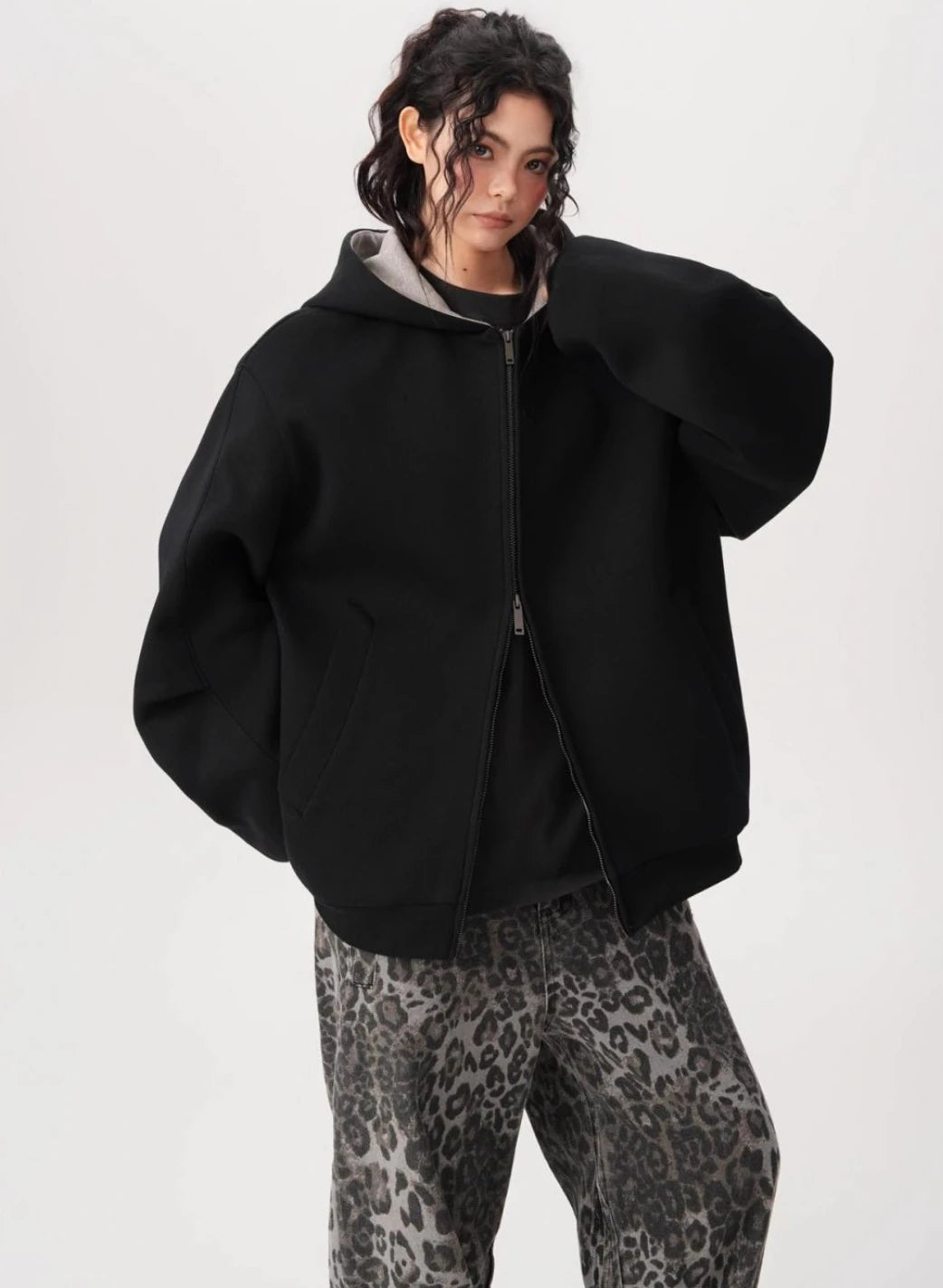 袖を少しまくったモデルがブラックオーバーサイズジップパーカーをラフに着こなしている正面コーデ写真