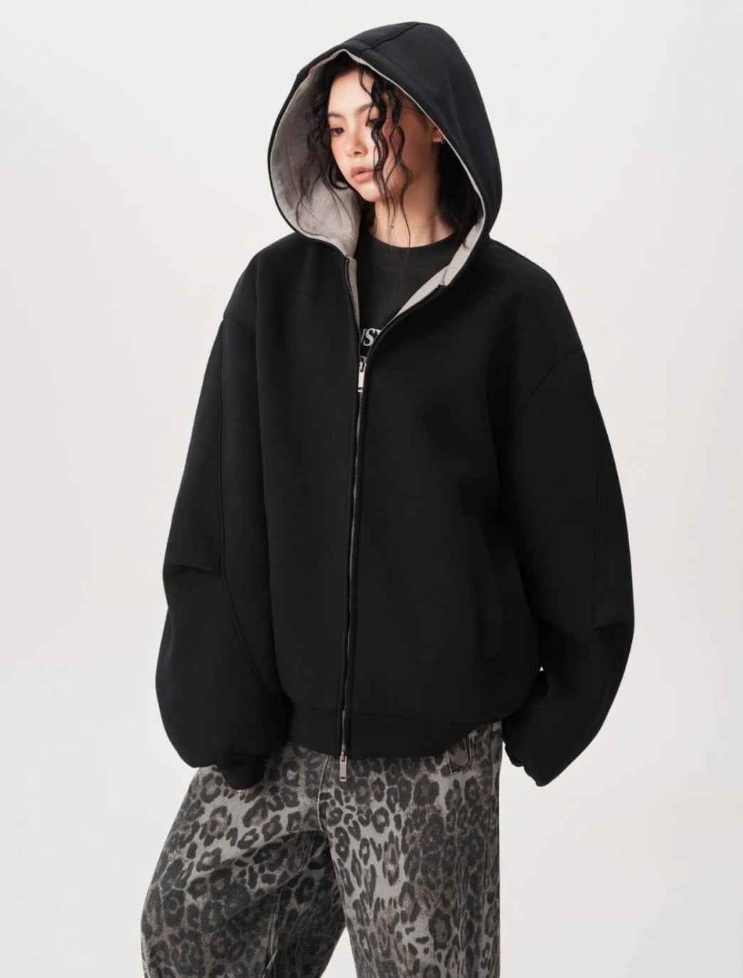 横向き気味のポーズでブラックオーバーサイズジップパーカーのフードとボリュームシルエットを見せている写真