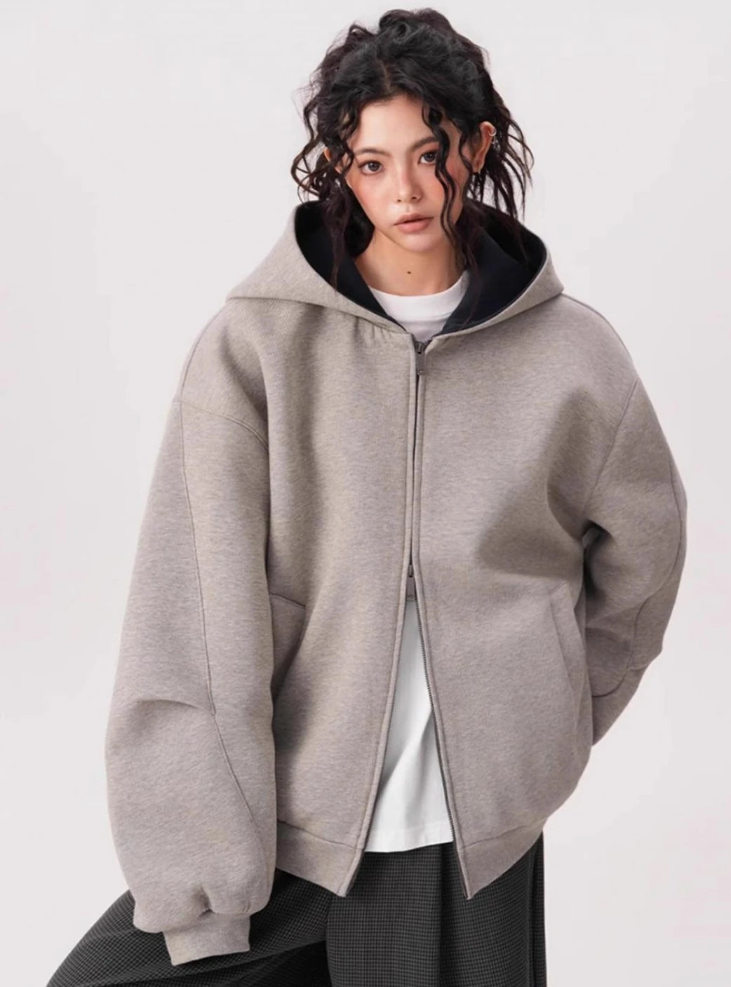 裏地がダークカラーのグレーオーバーサイズジップパーカーをモデルが前開きで着用している上半身写真