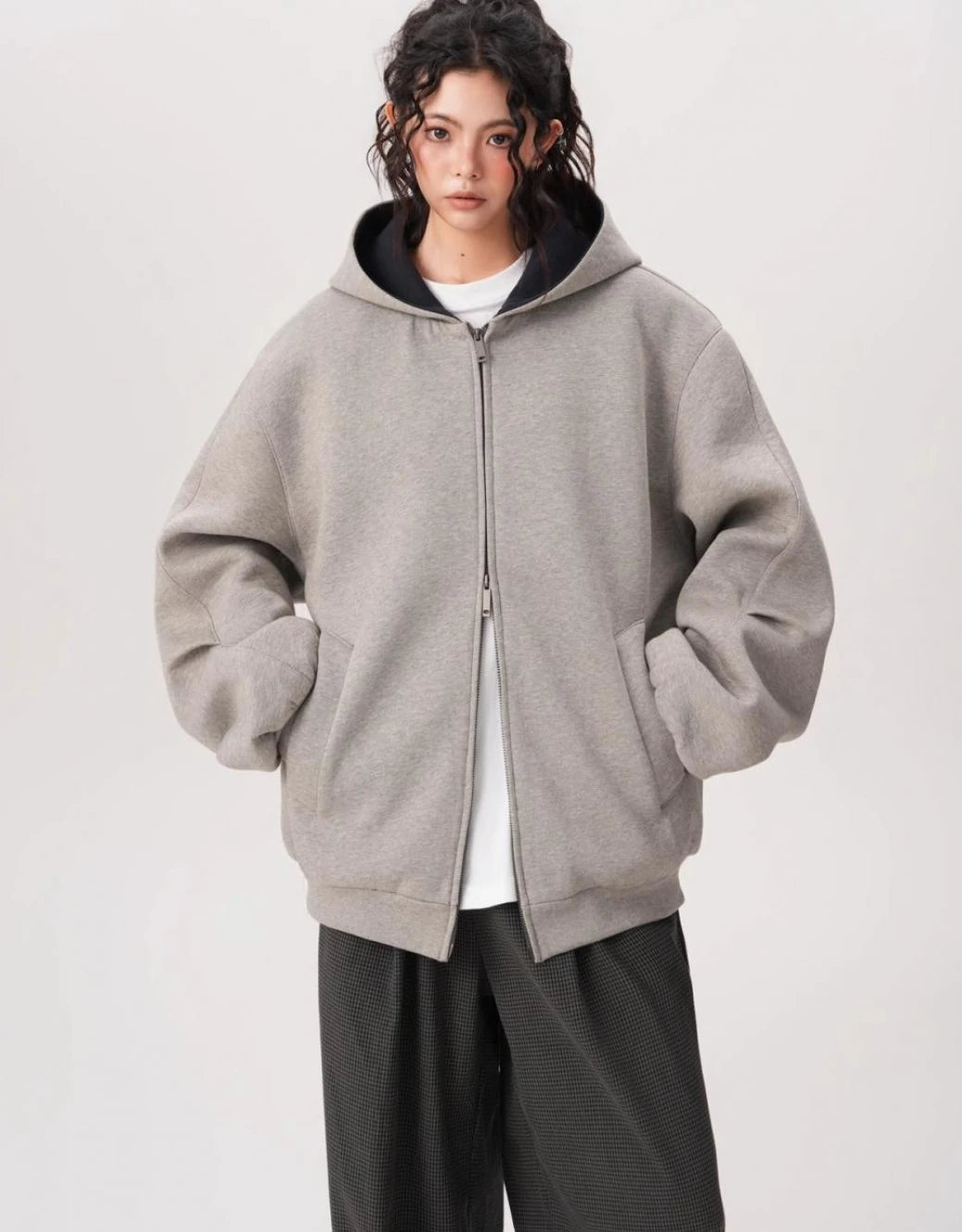 ポケットに手を入れたモデルがグレーのオーバーサイズジップパーカーを正面から着ている写真