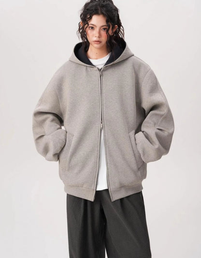ポケットに手を入れたモデルがグレーのオーバーサイズジップパーカーを正面から着ている写真