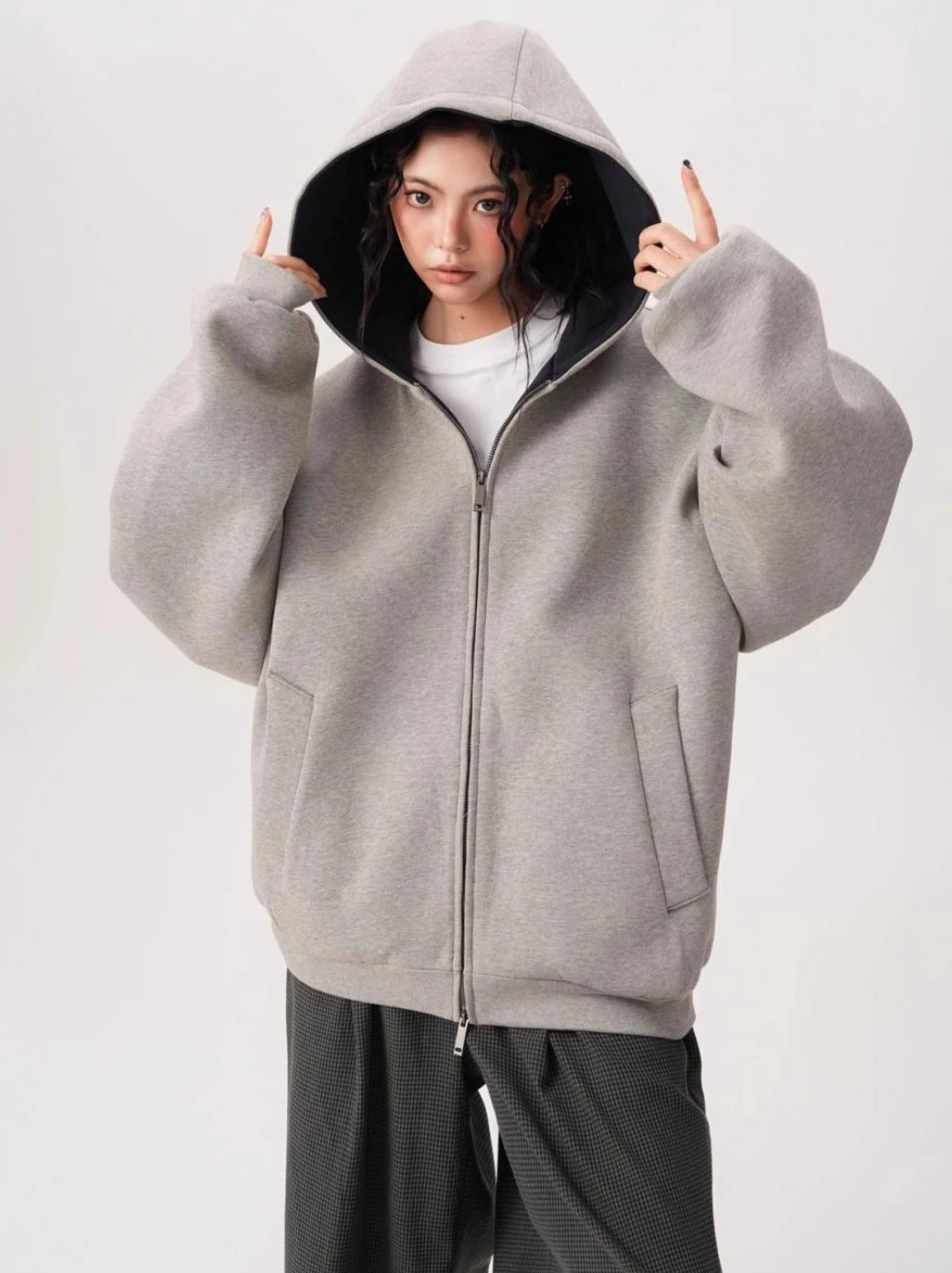 フードをかぶったモデルがグレーオーバーサイズジップパーカーを着用している前向きバストアップ写真