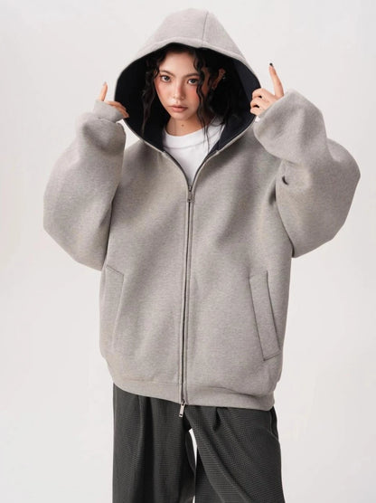 フードをかぶったモデルがグレーオーバーサイズジップパーカーを着用している前向きバストアップ写真