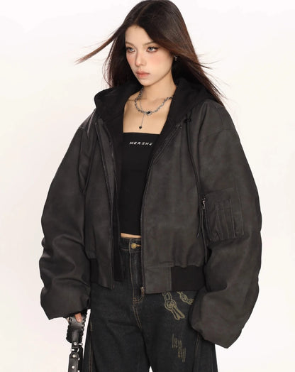 ブラックのオーバーサイズボンバージャケットを羽織り、斜め向きで片手にバッグのストラップを持ったモデルのウエストアップ