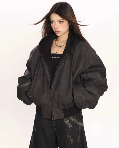 ブラックのオーバーサイズボンバージャケットを羽織り、横向き気味でポケットに手を入れたモデルの上半身ショット