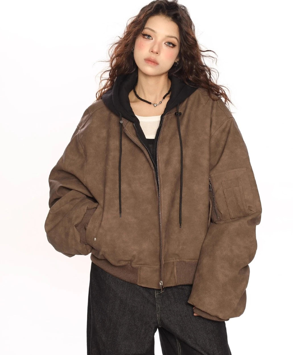 ブラウンのオーバーサイズボンバージャケットと黒パーカーを重ね着したモデルの正面上半身ショット