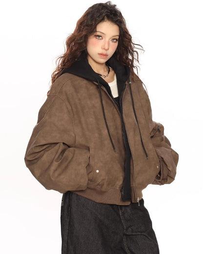 ブラウンのオーバーサイズボンバージャケットを羽織り、少し斜め向きでポケットに手を入れたモデルの上半身ショット