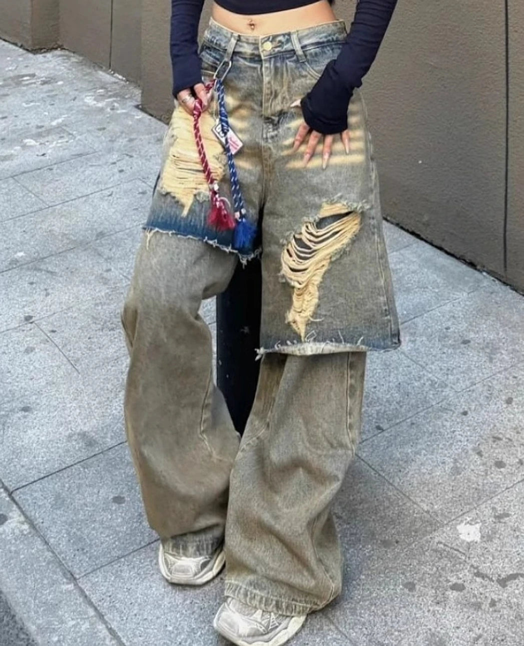 ダメージジーンズを着用し、手を腰に添えたポーズ。太もも部分の生地が二重になっているようなレイヤード風デザイン。