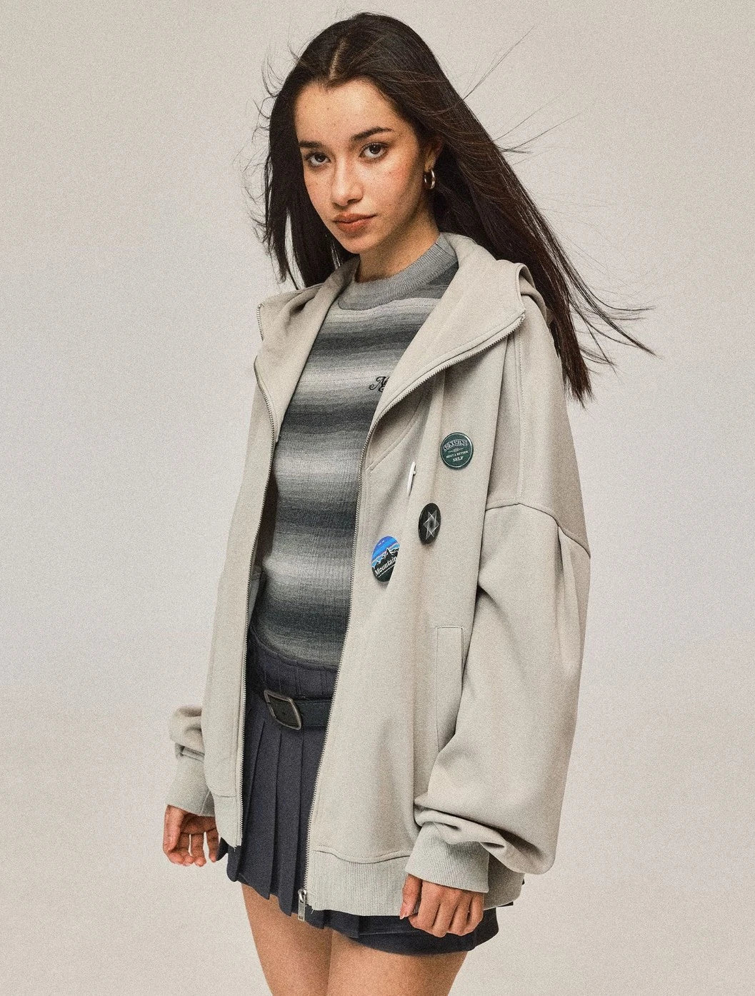 ジップを開けて着用したライトベージュのパーカー。インナーのボーダー柄トップスとのコーディネート。