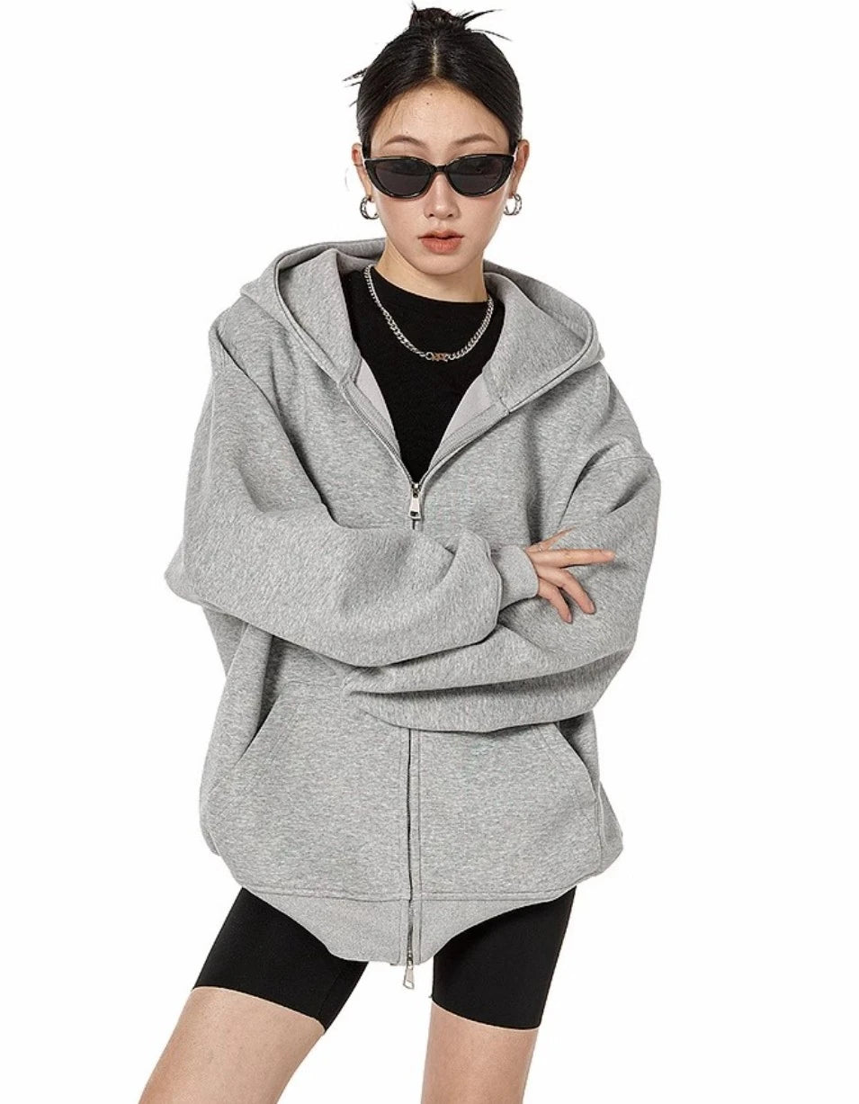 グレーのオーバーサイズジップパーカーをフルジップで閉め、腕を組んだモデルの正面上半身ショット