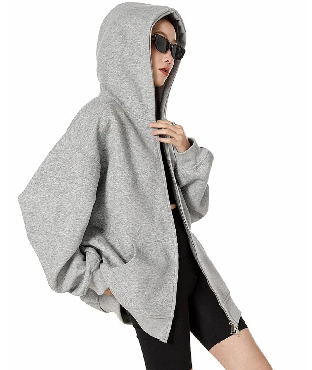 グレーのオーバーサイズジップパーカーのジップを少し開け、フードをかぶったまま斜め前を向くモデルのサイドスタイル