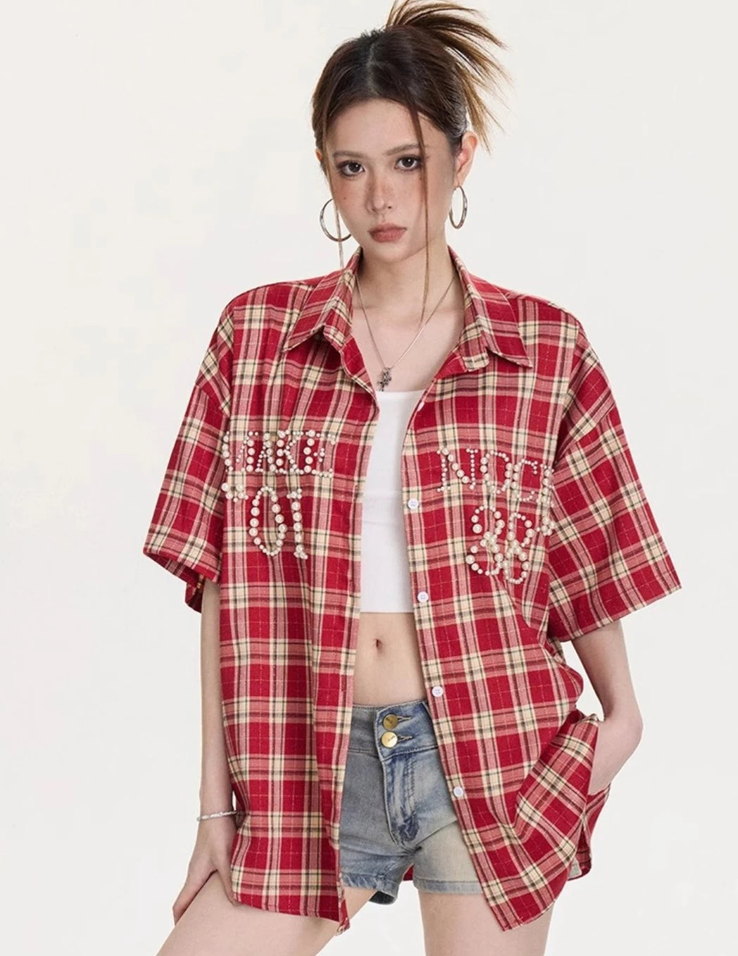 フロントポケットにパールのレタリング装飾が入ったレッドチェック柄オーバーサイズ半袖シャツの正面アップ。デニムショートパンツと合わせたスタイリング。