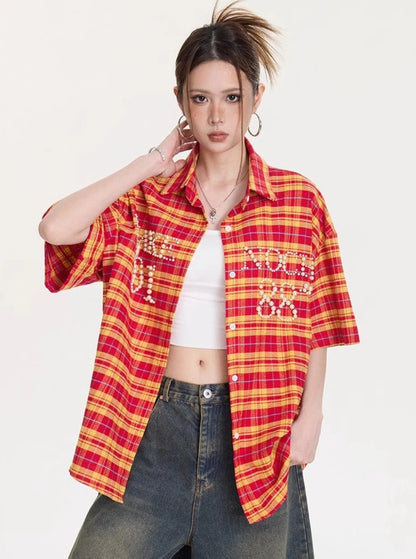 胸ポケットにパールレタリングが入ったイエロー×レッドチェック柄オーバーサイズシャツの正面アップ。インナーのホワイトタンクとデニムパンツを合わせたスタイリング。