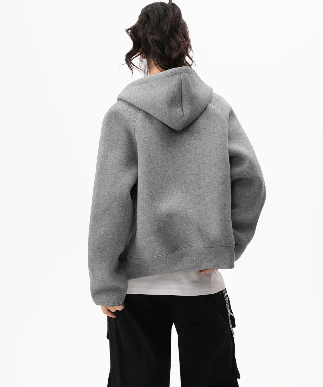 フードを下ろしたグレーのラグランジップパーカーのバックシルエットがわかる後ろ向き写真