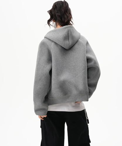 フードを下ろしたグレーのラグランジップパーカーのバックシルエットがわかる後ろ向き写真